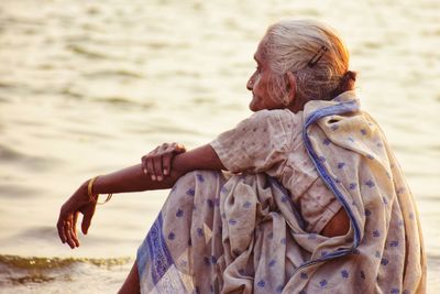 Side view of mature woman sitting at riverbank 