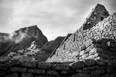 Low angle view of stone wall against cloudy sky