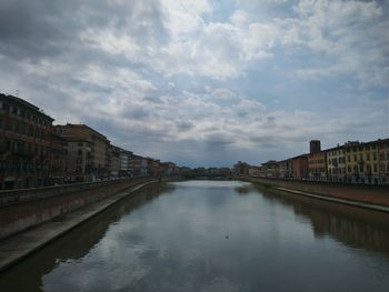 Arch bridge over canal amidst buildings in city against sky