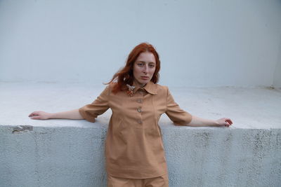 Portrait of young woman standing against wall