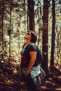 Side view of woman standing in forest