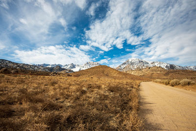 Scenic view of road by mountains against sky