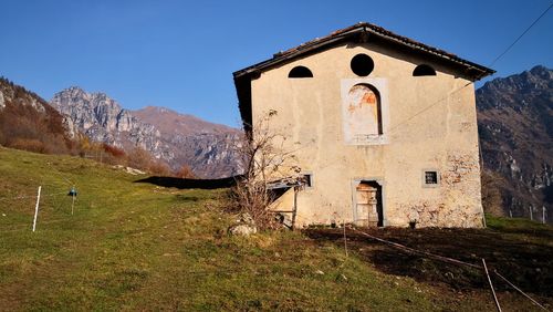 Rural housr by building against sky