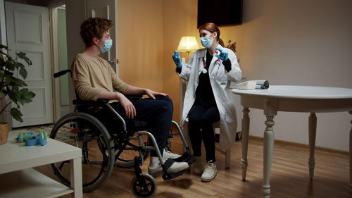 Doctor wearing mask examining patient at home