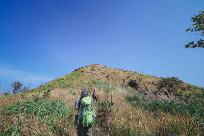 Low angle view of people hiking on mountain against sky