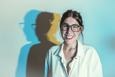 Portrait of young woman standing against wall