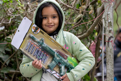 Portrait of smiling young woman standing against trees