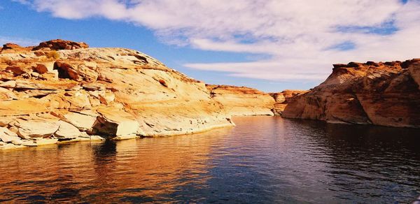 Scenic view of cliff by mountains against sky