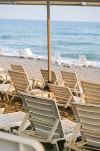 Chairs and table at beach against sky