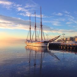 Boat moored at harbor against sky during sunset