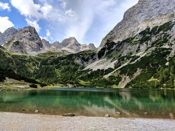 Scenic view of lake by mountains against sky