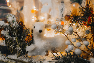 White toy fawn and christmas tree branch with silver glitter on a festive storefront. new year 2022