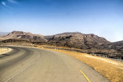 Empty road in desert against clear sky