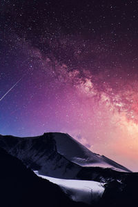 Scenic view of snowcapped mountains against sky at night