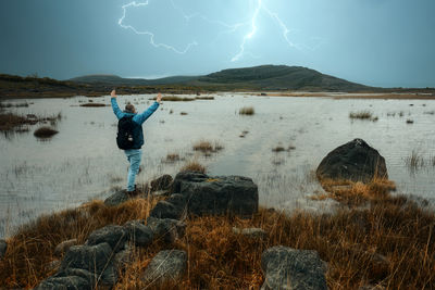 Man standing on the rock and watching thunderstorm lake and mountains at burren, clare, ireland
