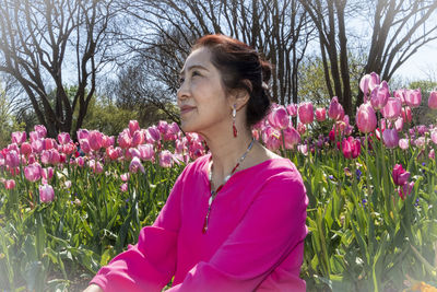 Woman standing by pink flowering plants