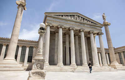 Tourist walking by parthenon against sky