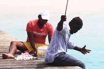 Men sitting on beach against sky