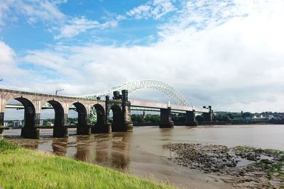 Bridge over river against cloudy sky