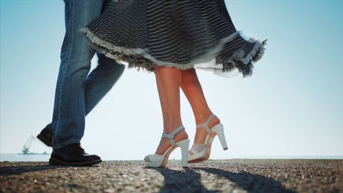 Low section of couple dancing on promenade against sky