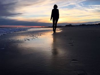 People standing on beach at sunset