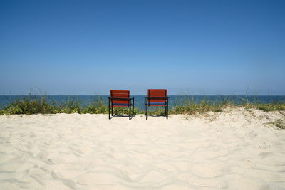 Chairs on sand against sea