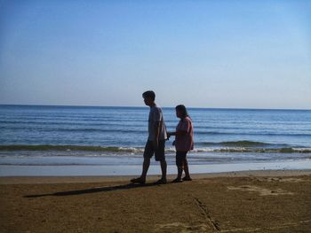 Full length of friends standing on beach against sea