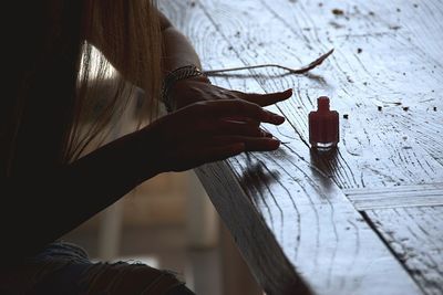 Cropped hands of woman painting fingernails on table