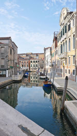 Canal amidst buildings in city against sky