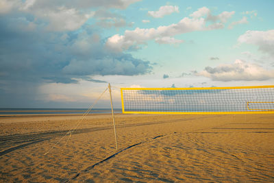 Beach volleyball net in sunset in front of sea