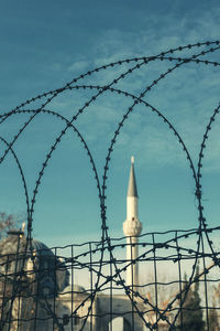 Low angle view of barbed wire fence against sky