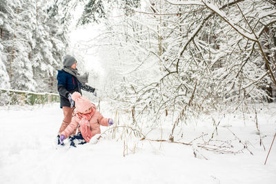 Full length of couple on snow covered tree during winter