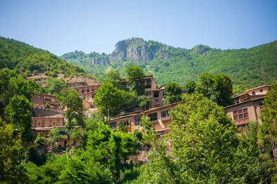 Scenic view of trees and houses against sky