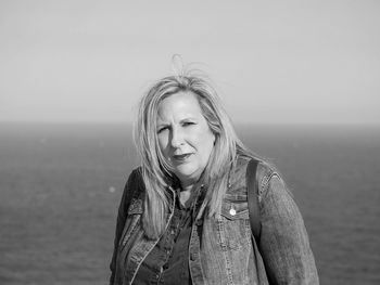 Portrait of woman standing by sea against sky