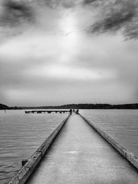 Pier on sea against cloudy sky