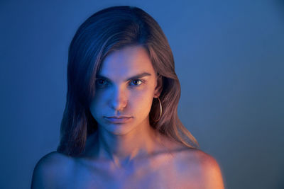 Portrait of young woman against blue background