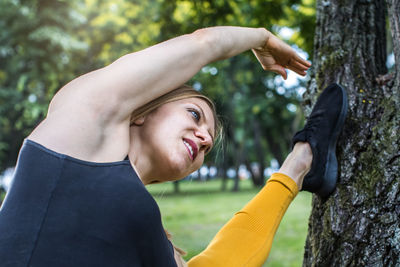Portrait of young woman stretching in the park