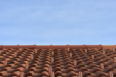 Low angle view of roof tiles against blue sky