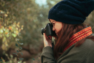 Woman holding camera while standing during winter
