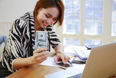 Young woman using phone while sitting on table