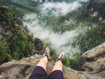 Low section of person on rock against waterfall