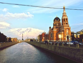 Canal amidst buildings against sky in city