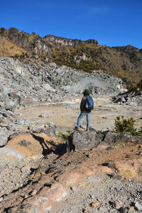 Rear view of man on standing on field against rock mountains