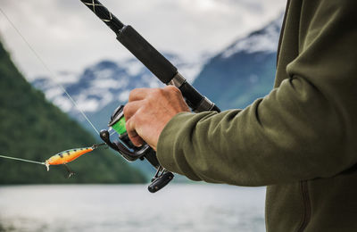 Midsection of man holding fishing rod