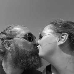 Low angle view of couple kissing against clear sky on sunny day