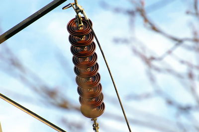 Low angle view of spiral hanging on rope against sky
