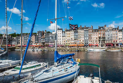 Sailboats moored on canal by buildings in city against sky