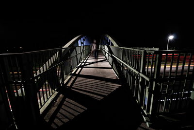 Illuminated footbridge against clear sky at night