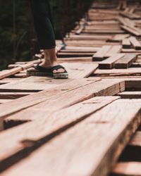 Low section of woman standing on wooden footbridge