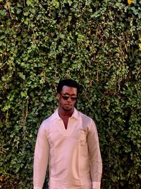 Portrait of young man standing against plants
